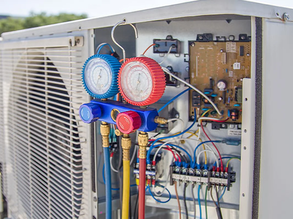 Technician testing the wiring inside an air conditioning control panel — AC and HVAC repair