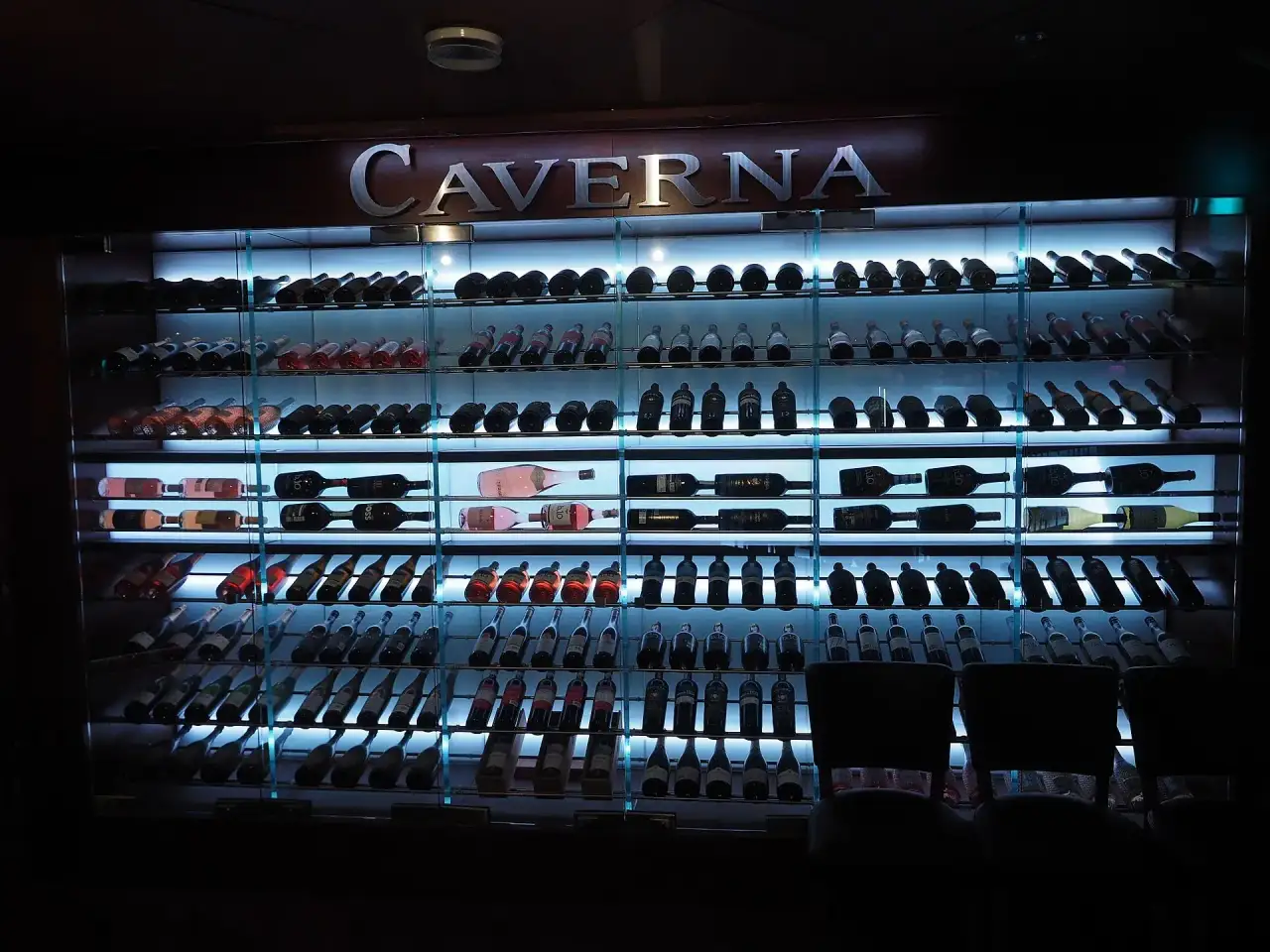 Illuminated glass-front wine cabinet filled with bottles — wine cellar cooling repair